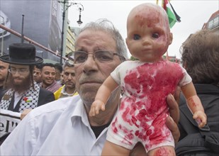 A Palestinian holds a doll coloured with red paint during the Al Quds demonstration in Berlin. Over