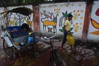 Cycle rickshaw rider washing his engine in the street, mural paintings, Hazaribagh, Jharkhand,