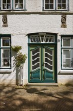 Entrance door with windows and rose bushes in Friedrichstadt, Nordfriesland district,