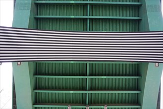 La Salve Bridge, underside of a bridge with green metal structure and striped banner, Old Town,