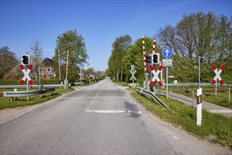 Gated level crossing with St Andrew's crosses and traffic lights for motor vehicles in Niebuell,