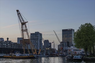 Harbour view with cranes, ships and skyscrapers in a slightly cloudy sky at dusk, small harbour in