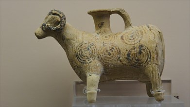 Antique pottery in the shape of a goat with elaborate circular ornaments on a beige background,