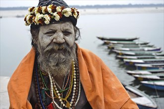 Portrait of a hindu ascetic, sadhu belonging to the naga order, Ganges river in the background,