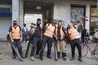 Employees of a cleaning service pose with their leaf blowers for a photo after the street parade of