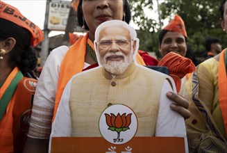 Bharatiya Janata Party (BJP) supporters holds a cutout of Narendra Modi as they arrives to to see a