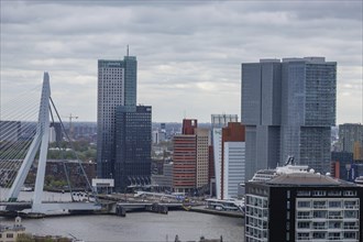 Closer view of a city with modern skyscrapers, a bridge and a river under a grey sky, view from