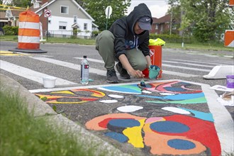 Detroit, Michigan, Artist Simone Lancaster paints a design on a city street. She is part of City