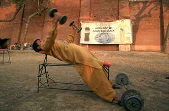 Young man lifting weights in a bodybuilding training place, Coca cola advertisement, Multan,