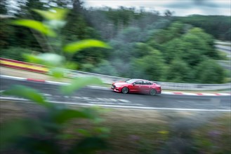 A red car travelling at high speed on a race track. Nuerburgring race track, Nuerburg Germany