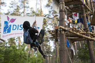 A person climbs up ropes to one of the tree houses in the occupied section of the Tesla Stop forest