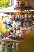 A stall at a market displays various bottles and food products on shelves, spring, Nagold, Black