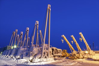 Cranes and equipment for oil production in the snow, twilight, Deadhorse, Alaska, USA, North