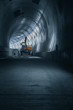 Dark tunnel with an excavator in the background, focussed light, tunnel construction Hermann