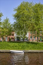 Motorboat on the Mittelburggraben with trees and houses in Friedrichstadt, district of
