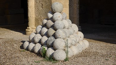 Large pyramid of stone cannonballs on a gravel floor, outdoor area, Archaeological Museum, Old
