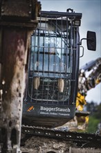 Close-up of the lattice cab of an excavator on a construction site, with company logo on the door,
