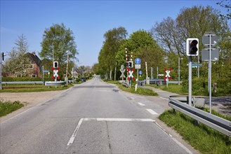 Gated railway crossing with traffic lights for motor vehicles in Niebuell, Nordfriesland district,