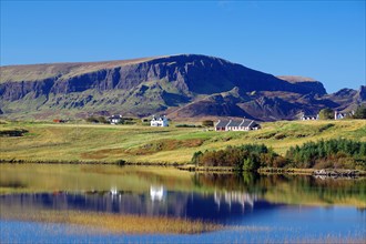Houses reflected in a small loch, high rugged mountains, Quarings, Isle of Skye, Scotland, Great