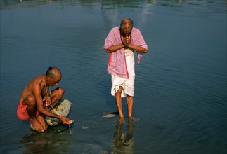 High caste hindu men performing a ritual, worshiing the sun god in the Gandaki river, Nepal, Asia