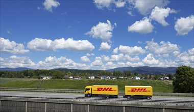 A DHL lorry drives past Deggendorf on the A3 motorway, with the Bavarian Forest in the background,