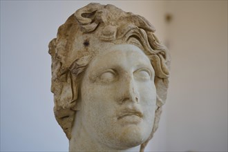 Helios, Sun God, Ancient marble sculpture of a damaged head with curly hair and pensive expression,
