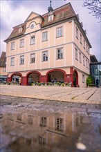 A historic town hall with a reflection in a puddle, cloudy sky, spring, Nagold, Black Forest,