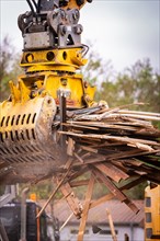 A hydraulic grab on an excavator grabs wood waste on a construction site, demolition, Saarbruecken,