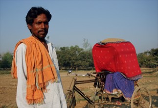 Cycle rickshaw rider, transporting a newlywed muslim couple, following the purdah tradition, Terai
