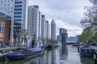 Waterway between modern skyscrapers and boats at dusk, small harbour in a big city with a
