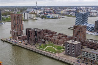 Modern skyscrapers and residential complexes along a river under a cloudy sky testify to urban