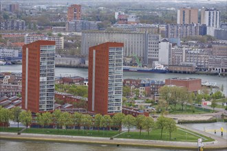 Cityscape with modern apartment blocks on the riverside and trees under a cloudy sky, view from