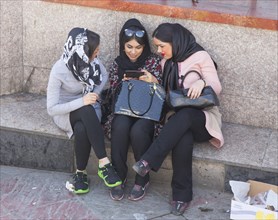 Three young Iranian woman look at a smart phone in Tehran on 07/04/2015, Tehran, Iran, Asia