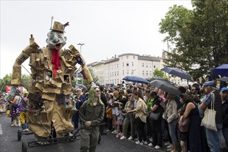 Sculpture by the Artistania group next to spectators with umbrellas at the street parade of the