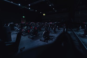 Dark gym with rows of indoor bikes under dimmed lights. Koblenz, Germany, Europe