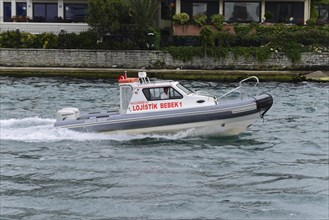 A white motorboat with the lettering 'Logistik Bebek' travelling fast across the water, Istanbul,