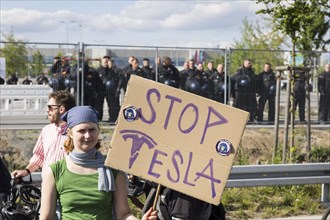 Participant with sign Stop Tesla in front of the Tesla Gigafactory at the demonstration Wasser.