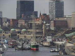 Close-up of a harbour with a large sailing ship and modern city buildings, many ships in a harbour