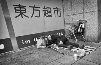 Homeless, Berber, sleeping, lying on pavement, Bible, shopping trolley, belongings, bag, Chinese