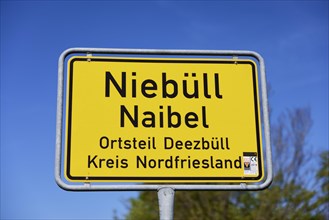 Town entrance sign against blue sky and blurred treetops, Deezbuell district, Niebuell,