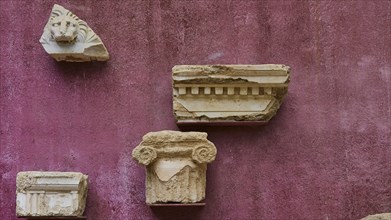 Architectural fragments of stone, ancient marble pieces attached to a wall, outdoor area,