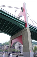 La Salve Bridge, A large bridge with red and green elements towering over buildings and