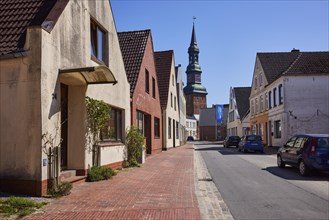 Street with houses and St Laurentius Church in Toenning, North Friesland district,
