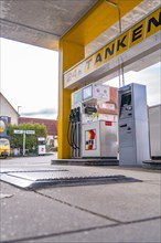 Modern petrol station in yellow with 24-hour service, petrol pumps and asphalt surface, Gechingen