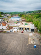 Aerial view of a construction site with vehicles and surrounding houses, roads and green areas