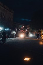 Atmospheric night shot of a busy street with food trucks and passers-by. Ehrenbreitstein Fortress,