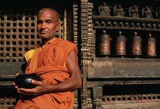 Theravada buddhist monk waiting for alms, nepalese man, Harati temple, Kathmandu valley, Nepal,