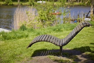 Public wooden deckchair on the banks of the Westersielzug in Friedrichstadt, North Friesland