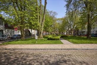 Park and cobblestone street in Friedrichstadt, Nordfriesland district, Schleswig-Holstein, Germany,