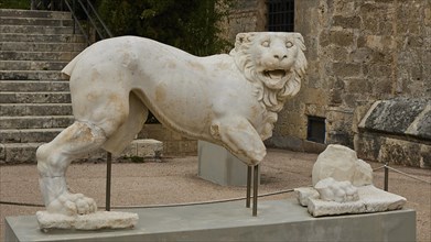 Incomplete antique marble sculpture of a mythological lion figure, placed outside, outdoor area,